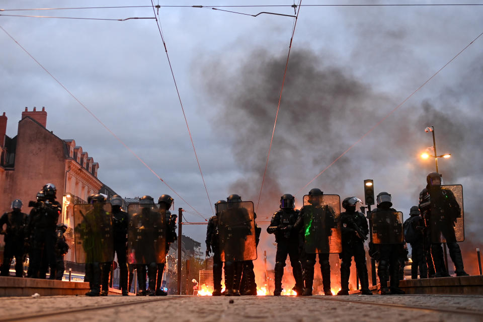 French anti-riot police officers stand in front of waste bins on fire during clashes with police on the sidelines of a demonstration after France's Constitutional Council approved the key elements of a pension reform, in Nantes, western France, on April 14, 2023.