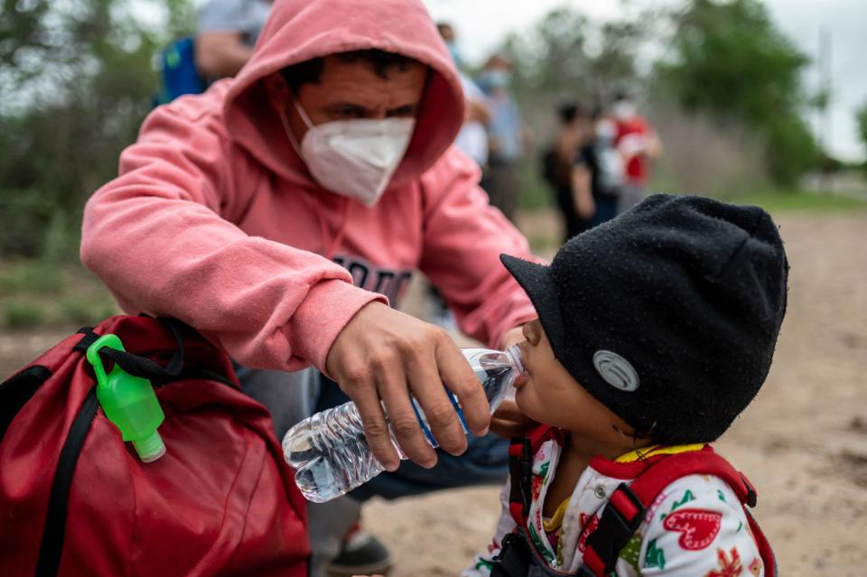 Nelson Alexsi Portillo Guillen gives his daughter Maria Amparo age 2, a drink of water, after being apprehended near the border between Mexico and the United States in Del Rio, Texas on May 16, 2021. / Credit: SERGIO FLORES/AFP via Getty Images