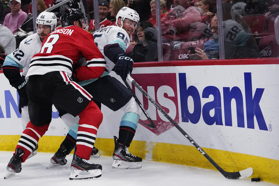 Seattle Kraken left wing Andre Burakovsky, right, battles for the puck against Chicago Blackhawks defenseman Jack Johnson during the first period of an NHL hockey game in Chicago, Sunday, Oct. 23, 2022. (AP Photo/Nam Y. Huh)