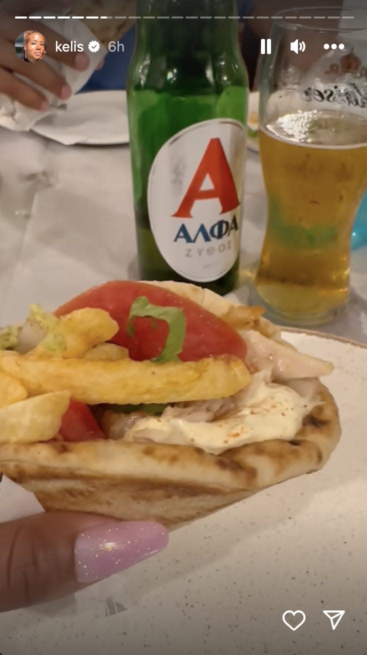 A picture of a pita sandwich with french fries and a beer