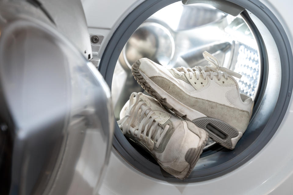 footwear hygiene - pair of dirty white sneakers in the washing machine