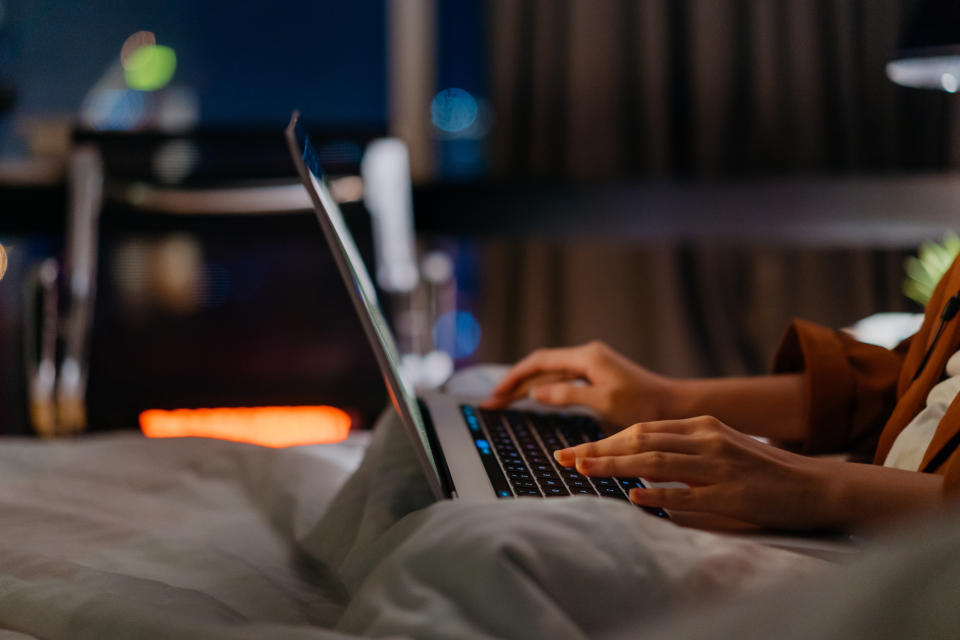 Close up of hand of a young asian woman working late in bed with a laptop