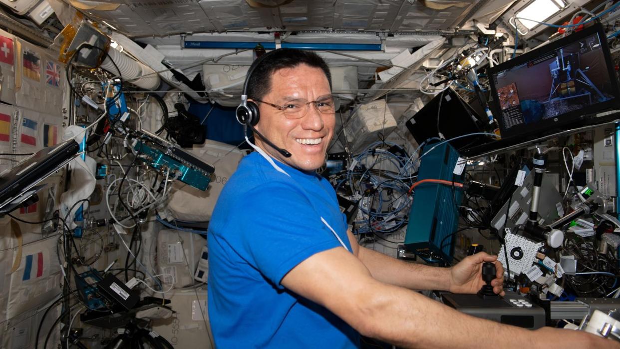  an astronaut floating in spies smiles while handling laboratory equipment 