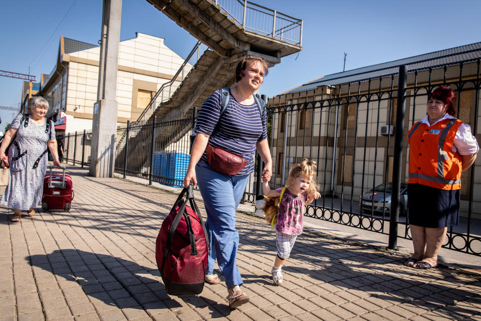 A woman boards an evacuation train with her daughter at the Pokrovsk Train Station in Ukraine