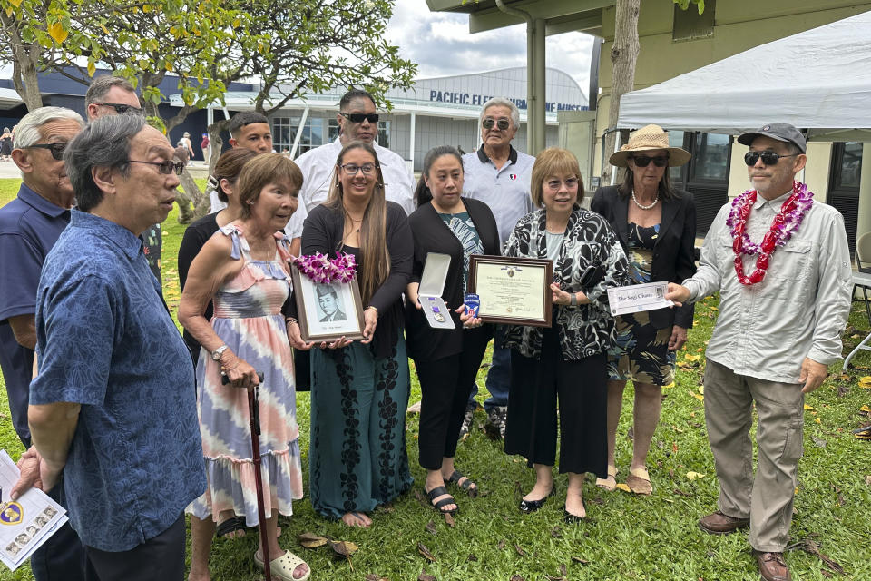 Members of the Sogi family hold a photo of Masaru Sogi and the Purple Heart medal posthumously awarded to him, in Pearl Harbor, Hawaii, on Friday, May 10, 2024. The families of five Hawaii men who served in a unit of Japanese-language linguists during World War II received posthumous Purple Heart medals on behalf of their loved ones on Friday, nearly eight decades after the soldiers died in a plane crash in the final days of the conflict. (AP Photo/Audrey McAvoy)