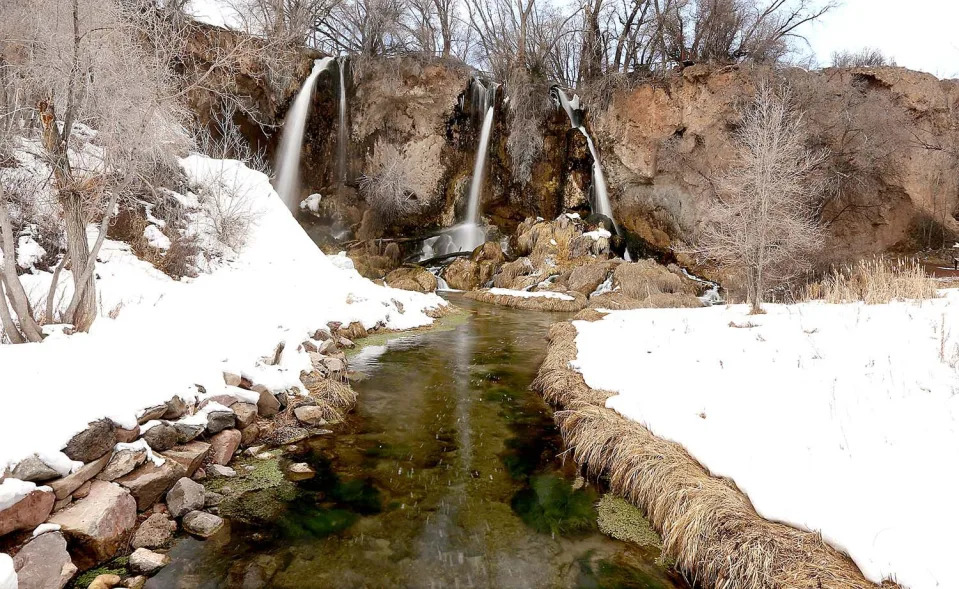 A waterfall and river are surrounded by snow