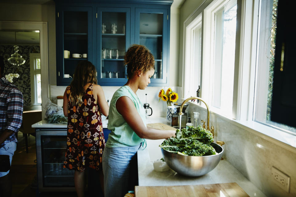 Two individuals preparing food in a kitchen with blue cabinets