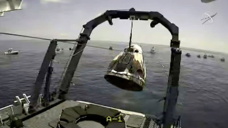 A capsule with NASA astronauts Robert Behnken and Douglas Hurley is lifted out of water in the Gulf of Mexico