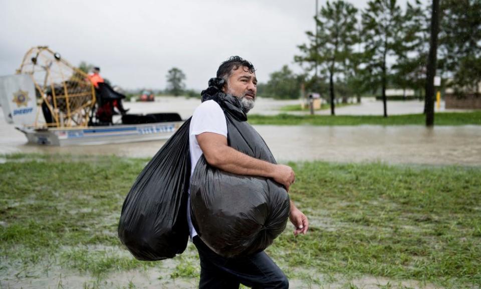 A man walks with belongings after being rescued from a flooded neighborhood in Houston.