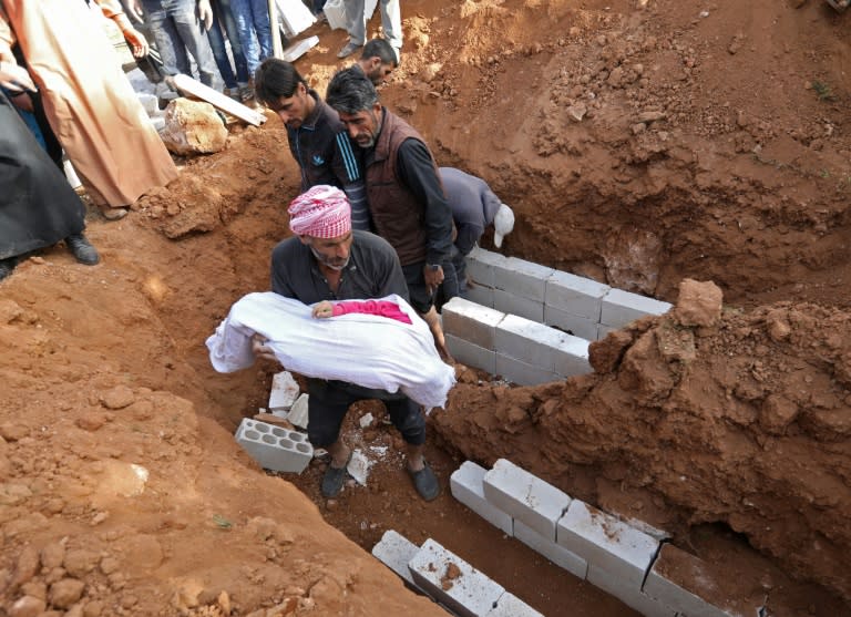 Syrians bury the bodies of children killed in an air strike in the northwestern province of Idlib on March 21, 2018