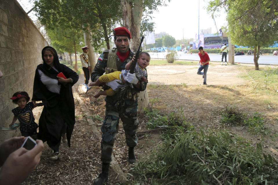 FILE - In this Saturday, Sept. 22, 2018 file photo provided by Mehr News Agency, an Iranian soldier carries a child away from a shooting during a military parade, in the southwestern city of Ahvaz, Iran. On Saturday, Arab separatists killed at least 25 people in an attack targeting the military parade in Iran, and President Donald Trump’s lawyer Rudy Giuliani declared that the Iranian government would be toppled. From Saturday’s attack in Ahvaz to America resuming sanctions despite Iran’s compliance with the 2015 nuclear deal, pressure on Tehran is rising and its leaders are growing more combative toward the West. (AP Photo/Mehr News Agency, Mehdi Pedramkhoo)