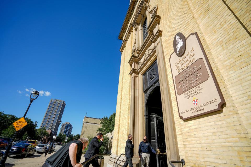 Three priests make their way into the public funeral for Archbishop Rembert Weakland on Tuesday, Aug. 30, 2022, at Cathedral of St. John the Evangelist  in downtown Milwaukee. A security guard was posted outside the cathedral door.