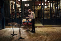 A waiter closes a bar terrace in Paris, Saturday Oct. 17, 2020. French restaurants, cinemas and theaters are trying to figure out how to survive a new curfew aimed at stemming the flow of record new coronavirus infections. The monthlong curfew came into effect Friday at midnight, and France is deploying 12,000 extra police to enforce it. (AP Photo/Lewis Joly)