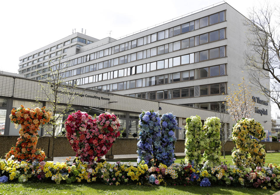 Flowers are arranged in the shape of letters outside St Thomas' Hospital in central London as British Prime Minister Boris Johnson is in intensive care fighting the coronavirus in London, Tuesday, April 7, 2020. Johnson was admitted to St Thomas' hospital in central London on Sunday after his coronavirus symptoms persisted for 10 days. Having been in hospital for tests and observation, his doctors advised that he be admitted to intensive care on Monday evening. The new coronavirus causes mild or moderate symptoms for most people, but for some, especially older adults and people with existing health problems, it can cause more severe illness or death.(AP Photo/Kirsty Wigglesworth)