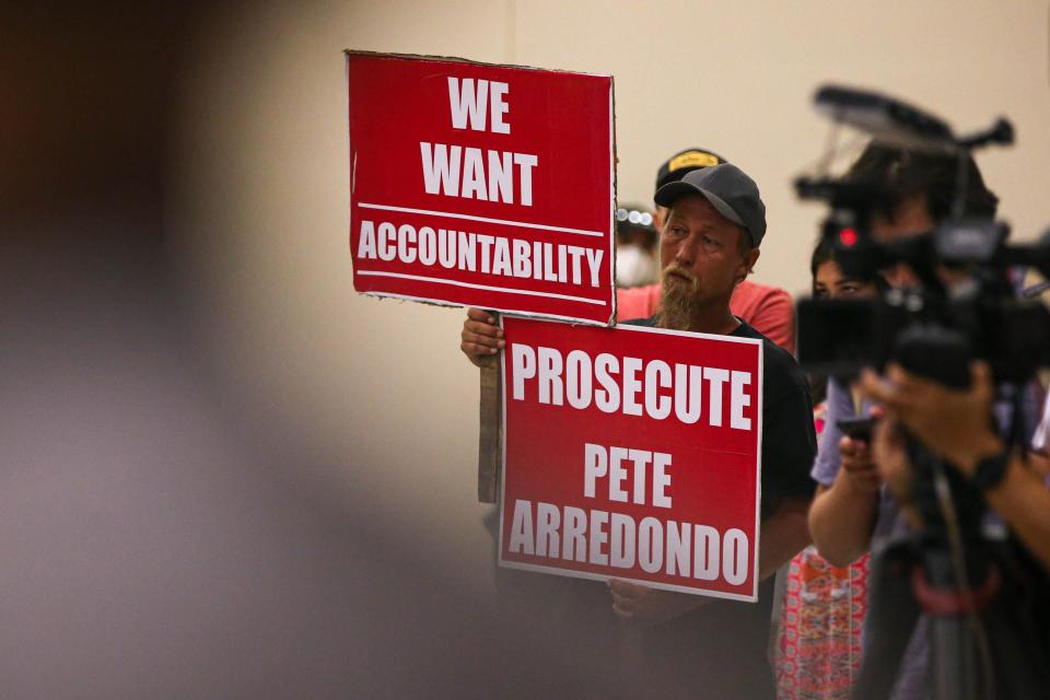 Michael Brown, an Uvalde community member with a child that was enrolled at Robb Elementary, holds signs calling for police accountability during a July 17 public hearing in Uvalde,