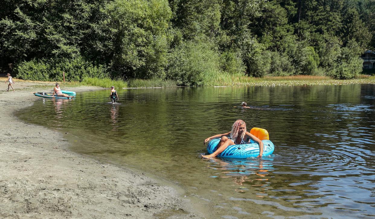 Aniya Jackson, 19, pushes off from the Island Lake beach aboard her floating tube while taking advantage of the warm weather on Monday, Aug. 14, 2023.