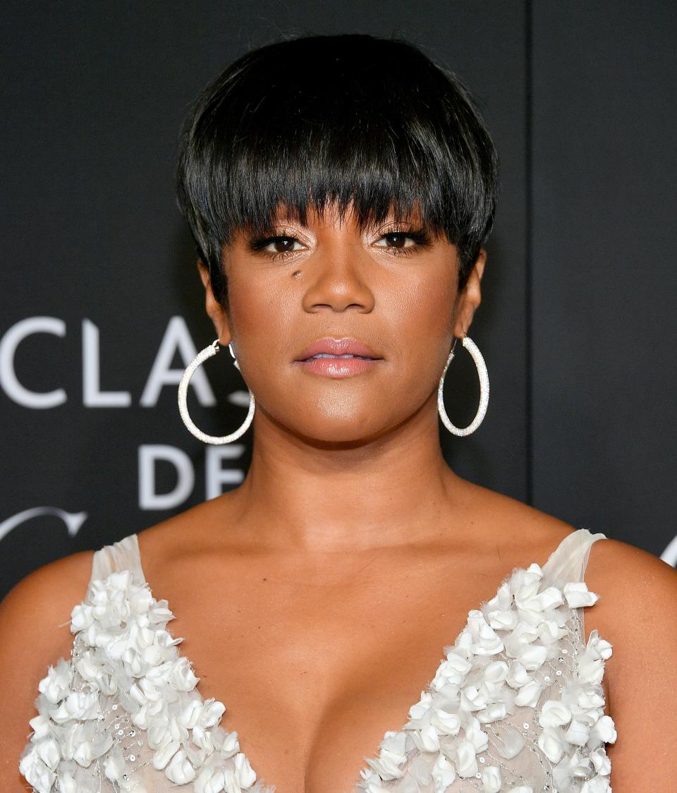 Tiffany Haddish with short hair in an embellished gown with flower details and a bow