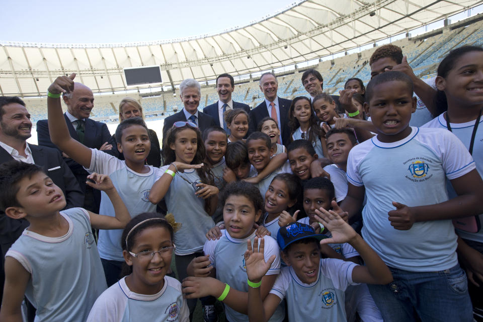 Britain's Chancellor of the Exchequer George Osborne, back row center, standing next to President of Brazil's Olympic Committee Carlos Arthur Nuzman, right center, in red tie, poses for a photo with children during a visit to the Maracana stadium in Rio de Janeiro, Brazil, Monday, April 7, 2014. The city of Rio de Janeiro will host the Olympics in 2016. (AP Photo/Silvia Izquierdo)