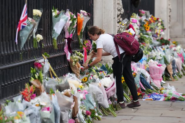 A woman pauses next to flowers and tributes to Queen Elizabeth II outside Buckingham Palace on September 9, 2022. (Photo: Carl Court via Getty Images)