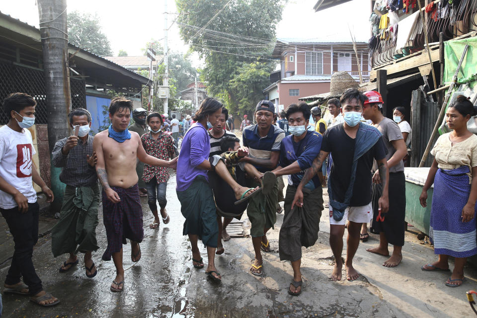 Varios manifestantes trasladan a un hombre herido a un lugar seguro después de que la policía usó la fuerza para dispersarlos el sábado 20 de febrero de 2021, en Mandalay, la segunda ciudad más grande de Myanmar. (AP Fotos)