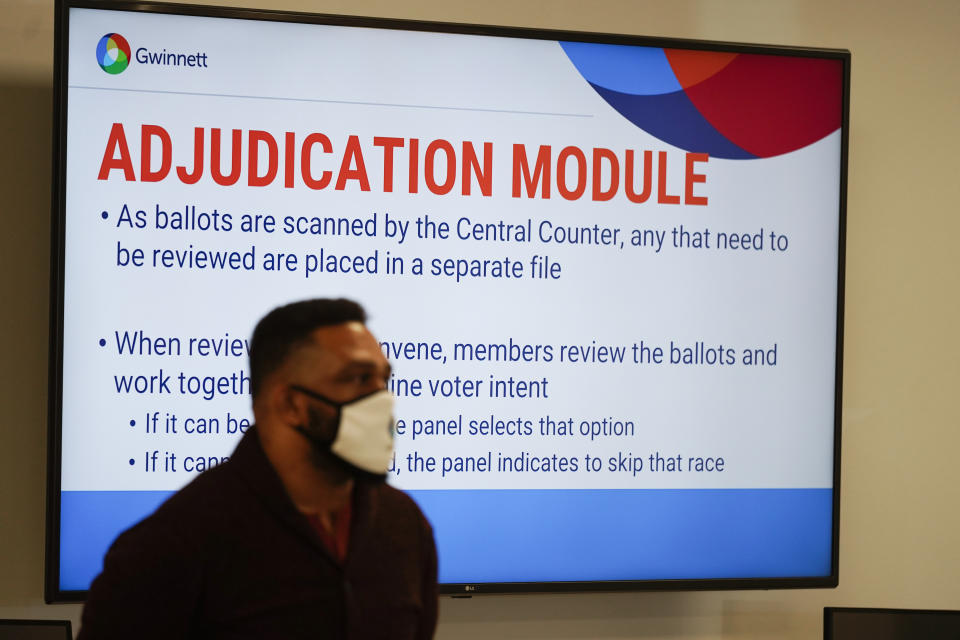 A poll worker looks on as officials survey ballots at the Gwinnett County Voter Registration and Elections Headquarters, Friday, Nov. 6, 2020, in Lawrenceville, near Atlanta. (AP Photo/John Bazemore)