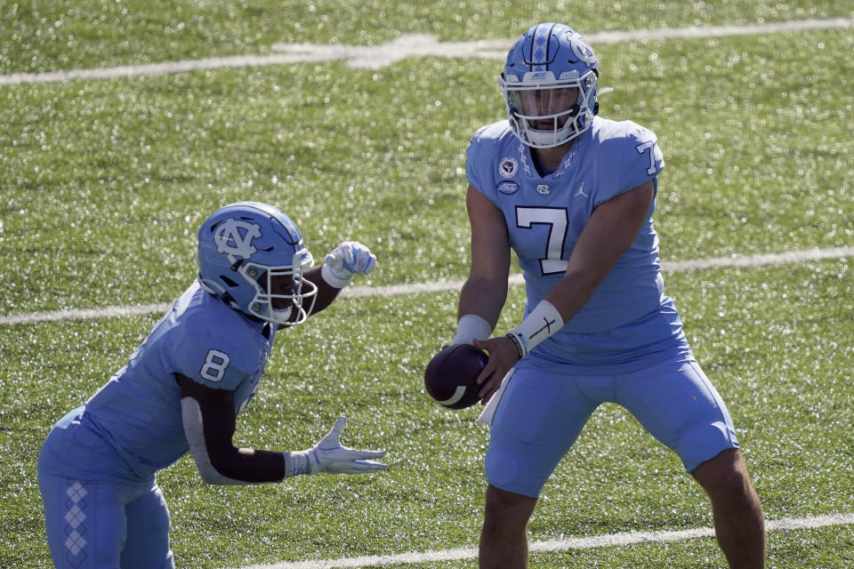 North Carolina quarterback Sam Howell (7) hands off the ball to running back Michael Carter (8) during the first half of an NCAA college football game against North Carolina State in Chapel Hill, N.C., Saturday, Oct. 24, 2020. (AP Photo/Gerry Broome)