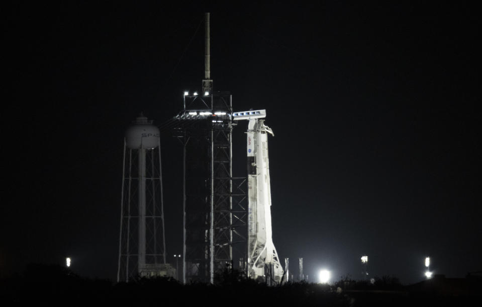 A SpaceX rocket with the company's Dragon capsule is illuminated by spotlights on the launch pad, early Friday, April 23, 2021, at NASA's Kennedy Space Center in Cape Canaveral, Fla. SpaceX aimed to launch its third crew a little before sunrise Friday, this time using a recycled capsule and rocket. The four astronauts, representing the U.S., Japan and France, were supposed to fly to the International Space Station on Thursday. But liftoff was delayed because of poor weather offshore. (Joel Kowsky/NASA via AP)