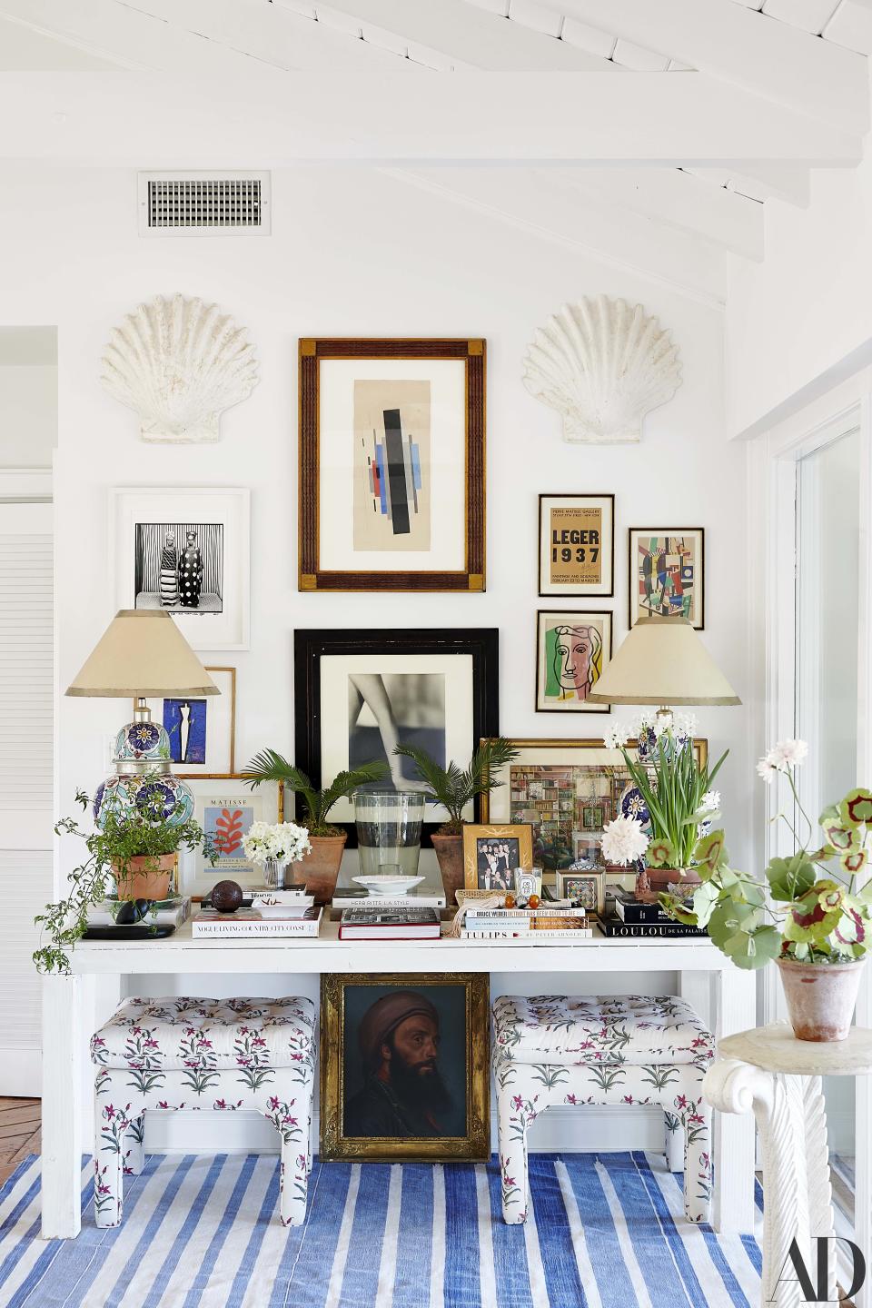 Artworks by Ilia Tchachnik, Malick Sidibé, and Fernand L´éger hang above a custom table; the Palm Beach Regency stools are covered in Brigitte Singh fabric.