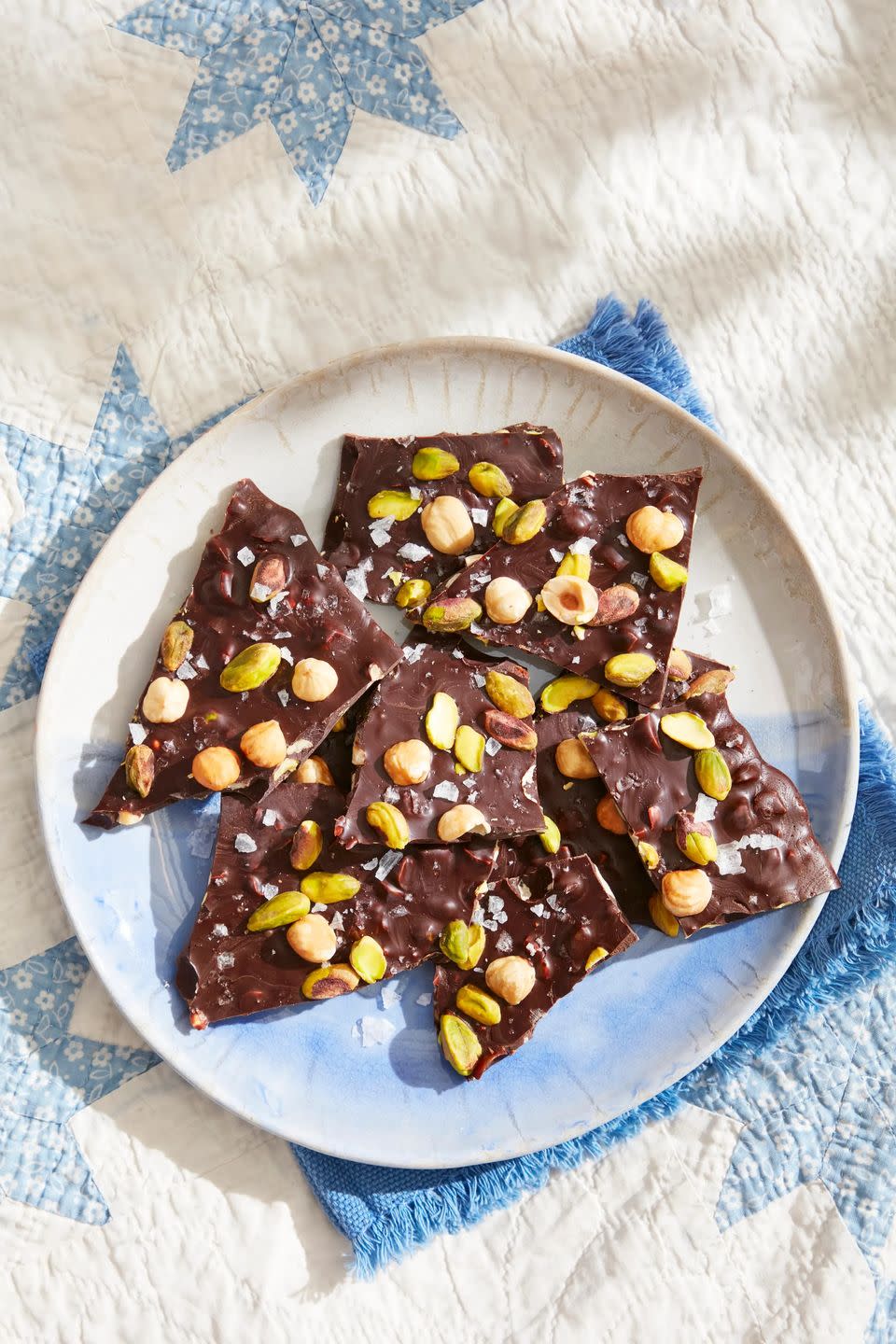 roasted hazelnut pistachio dark chocolate bark on a plate on a picnic blanket