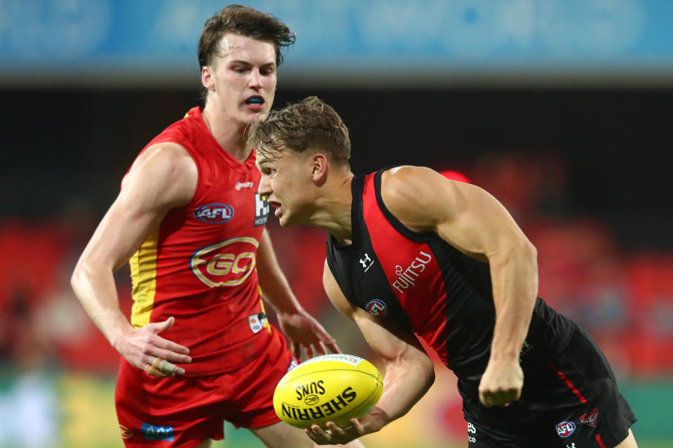 Dylan Clarke of the Bombers handballs during the round 11 AFL match between the Gold Coast Suns and the Essendon Bombers.