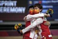 Shanju Bao, left, and Tianshi Zhong of Team China hug with their gold medals during a medal ceremony for the track cycling women's team sprint finals at the 2020 Summer Olympics, Monday, Aug. 2, 2021, in Izu, Japan. (AP Photo/Christophe Ena)