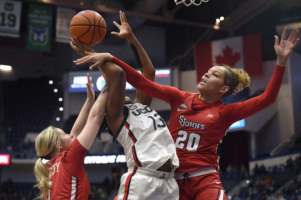 St. John's Rayven Peeples (20) fouls Connecticut's Christyn Williams (13) as St. John's Sara Zabrecky defends during the first half of an NCAA college basketball game Friday, Feb. 25, 2022, in Hartford, Conn. (AP Photo/Jessica Hill)