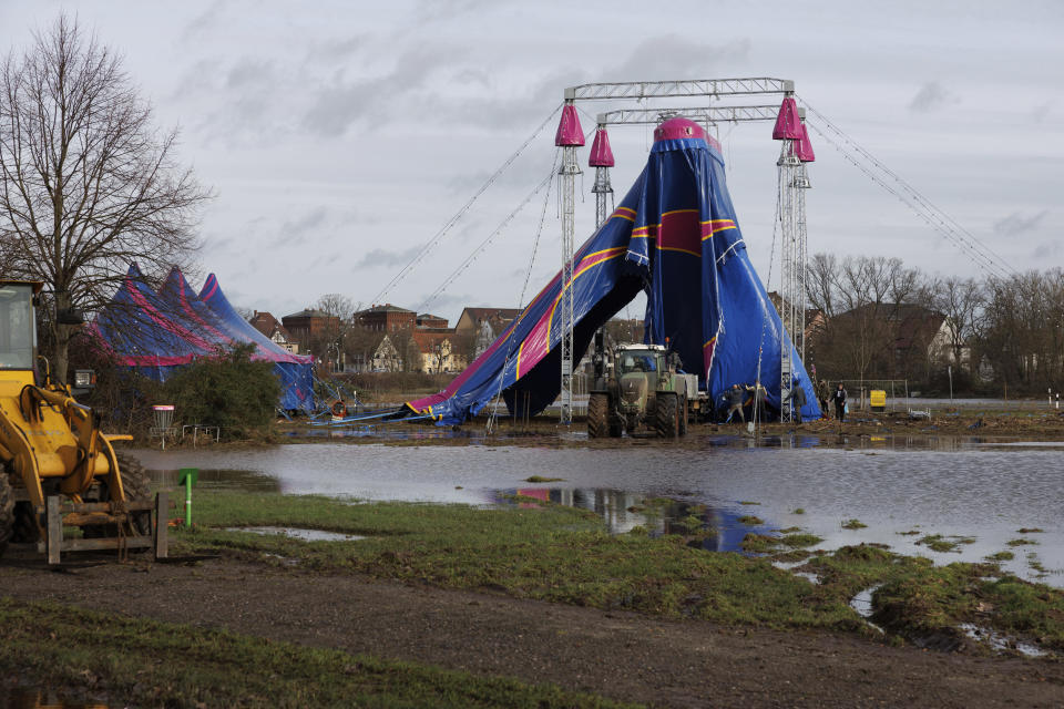 A circus tent is dismantled on the flooded banks of the Weser, in Minden, Germany, Saturday Dec. 30, 2023. Despite a slight easing of water levels, numerous streams and rivers in North Rhine-Westphalia continue to flood. (Friso Gentsch/dpa via AP)