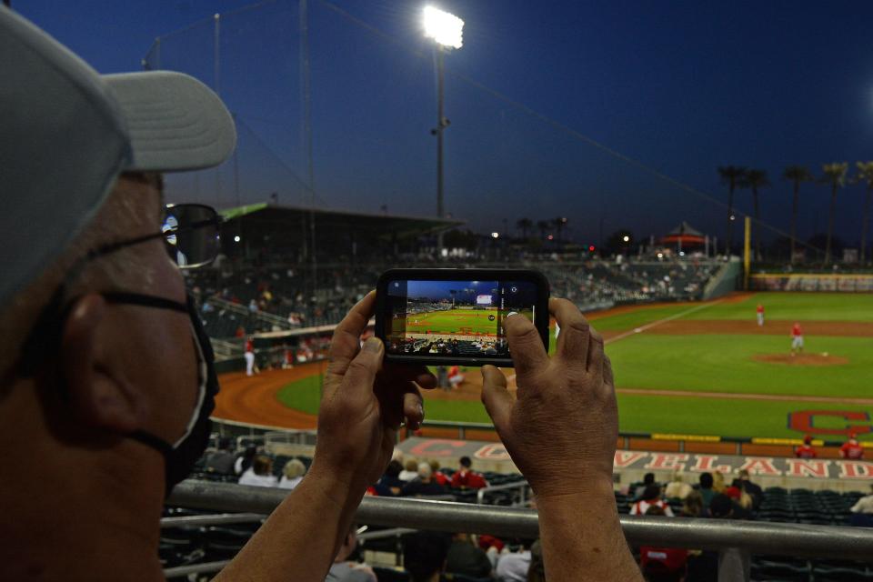 A fan takes a photo on their phone of general view of game action between the Cincinnati Reds and the Los Angeles Angels during the second inning of a spring training game at Goodyear Ballpark.