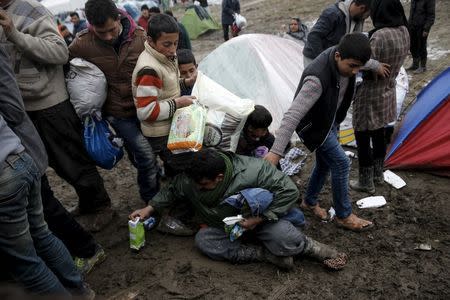 A man falls on the ground as refugees and migrants grab goods donated by volunteers from a truck at a makeshift camp at the Greek-Macedonian border, near the village of Idomeni, Greece March 16, 2016. REUTERS/Alkis Konstantinidis