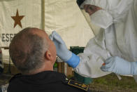 A medical staffer performs swabs to test for coronavirus, in the Military barracks of Cecchignola in Rome, Tuesday, Oct. 27, 2020. As Italy faces a new wave of COVID-19 infections, the Italian military is helping healthcare services in the effort to contain infection. Defense minister Lorenzo Guerini has signed an agreement with the Ministry of Health Ministery to provide temporary drive-through structures in to perform nose and throat swabs to increase the daily Covid-19 testing capacity of the country. (AP Photo/Andrew Medichini)