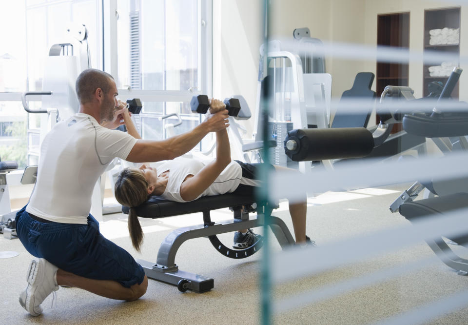 Two people engaged in a workout, one spotting the other with weights