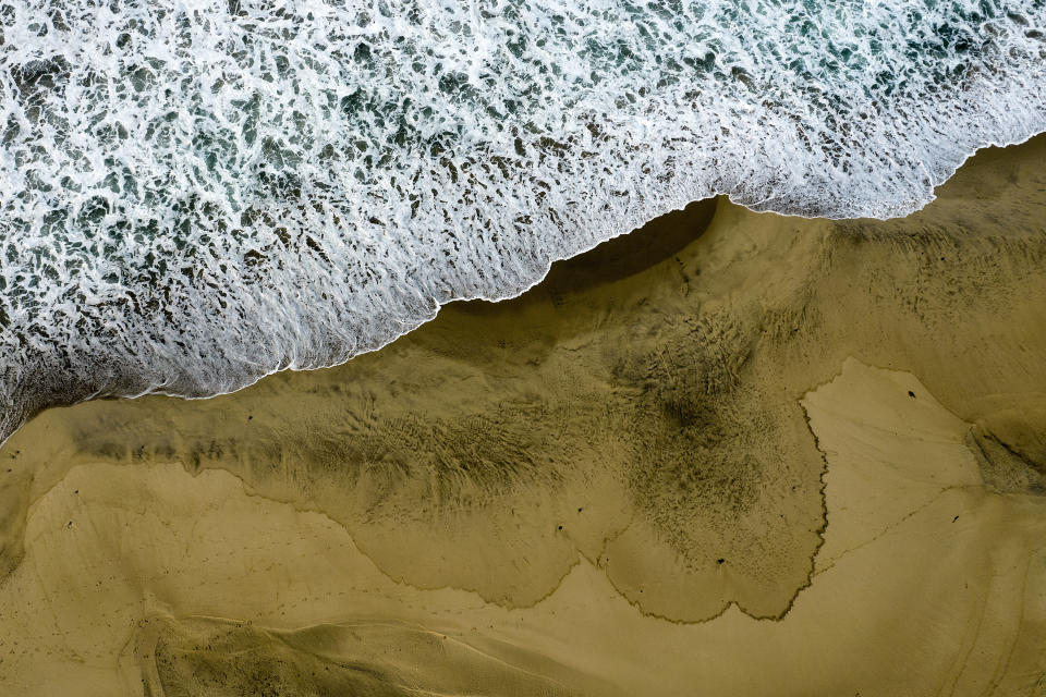 An aerial photo shows the closed beach after oil washed up on Huntington Beach, Calif., on Monday, Oct. 4, 2021. A major oil spill off the coast of Southern California fouled popular beaches and killed wildlife while crews scrambled Sunday, to contain the crude before it spread further into protected wetlands. (AP Photo/Ringo H.W. Chiu)