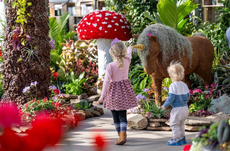 Mae Kellerman, 5, and her brother, Brooks Dudzinski, 2, of Overland Park, visit a whimsical garden display inside Shawnee’s greenhouse.