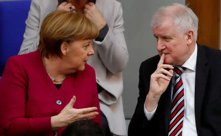 FILE PHOTO: German Chancellor Angela Merkel talks to Interior Minister Horst Seehofer during a session of the Bundestag in Berlin, Germany, March 21, 2018. REUTERS/Fabrizio Bensch/File Photo