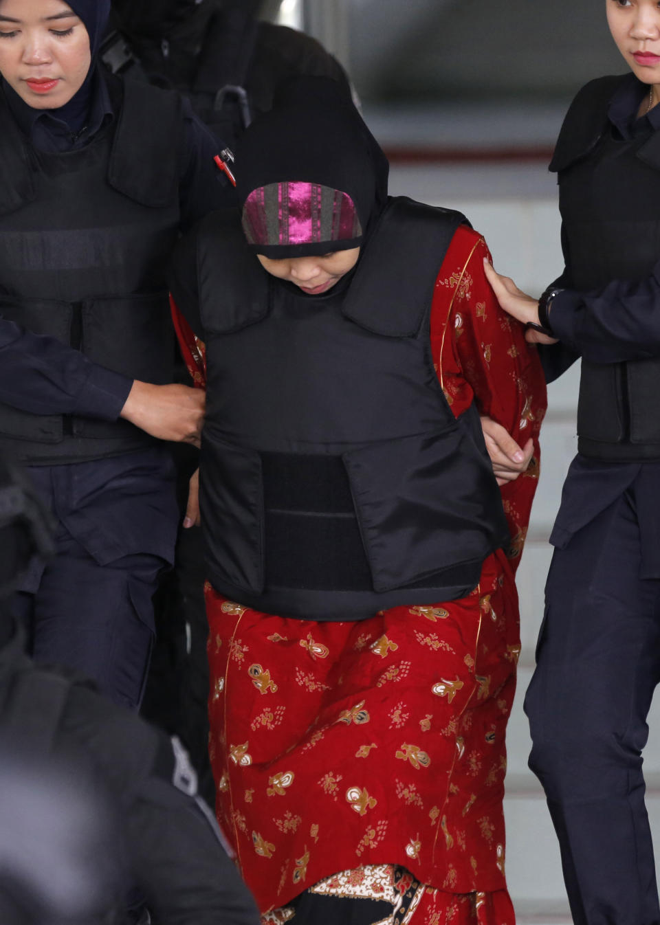 Indonesian Siti Aisyah is escorted by police as she leaves after court hearing at Shah Alam High Court in Shah Alam, Malaysia, Thursday, Aug. 16, 2018. Malaysian court has ordered the two women, Siti Aisyah and Vietnam's Doan Thi Huong, to enter their defense over the murder of North Korean leader's half brother in a brazen assassination that has gripped the world. (AP Photo/Yam G-Jun)