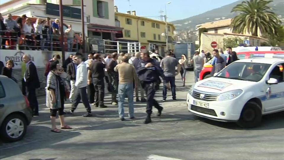 In this image from TV, Police cordon off the area as people gather to view the nearby high school, following a shooting in Grasse, southern France, Thursday March 16, 2017. According to officials, an armed high school student attacked at the Alexis de Tocqueville high school in the town of Grasse, France. At Least two people are known to be injured. (BFM via AP)