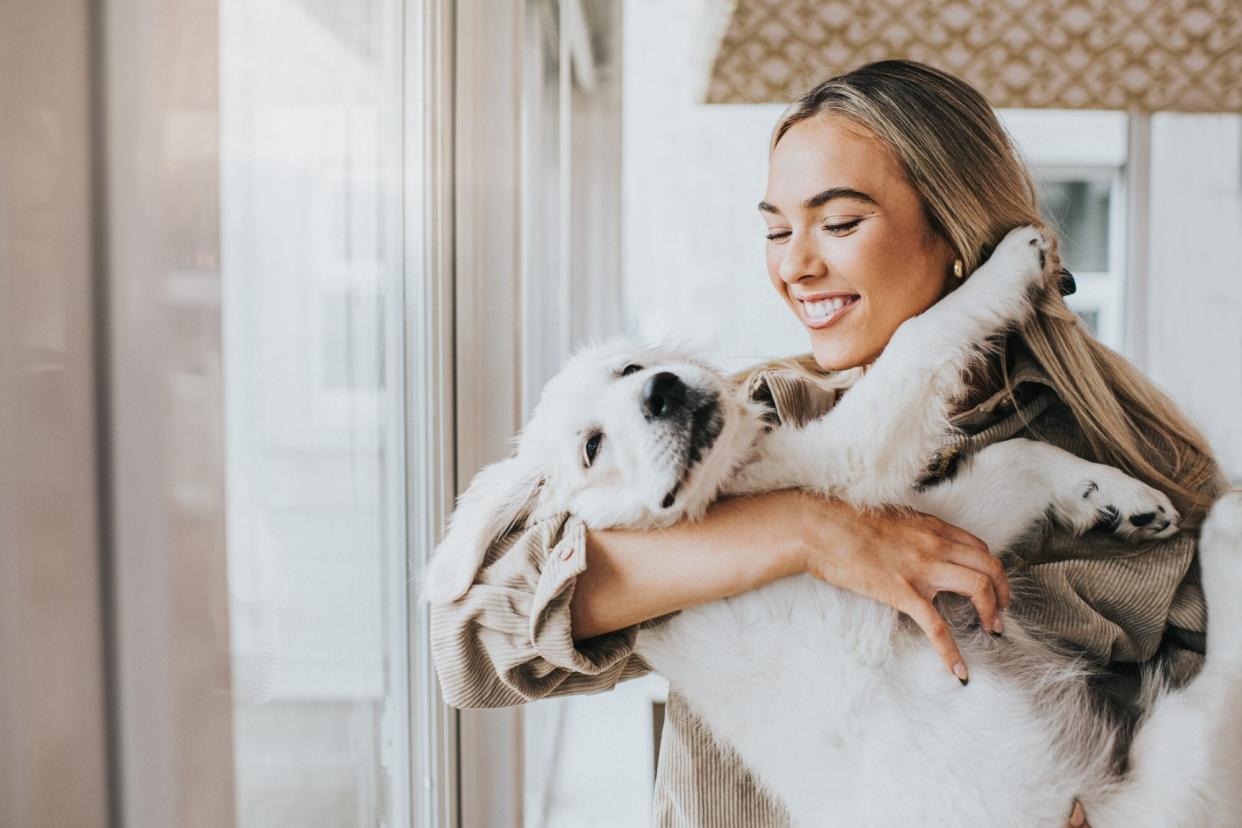 Young woman holds golden retriever puppy in her arms like a baby