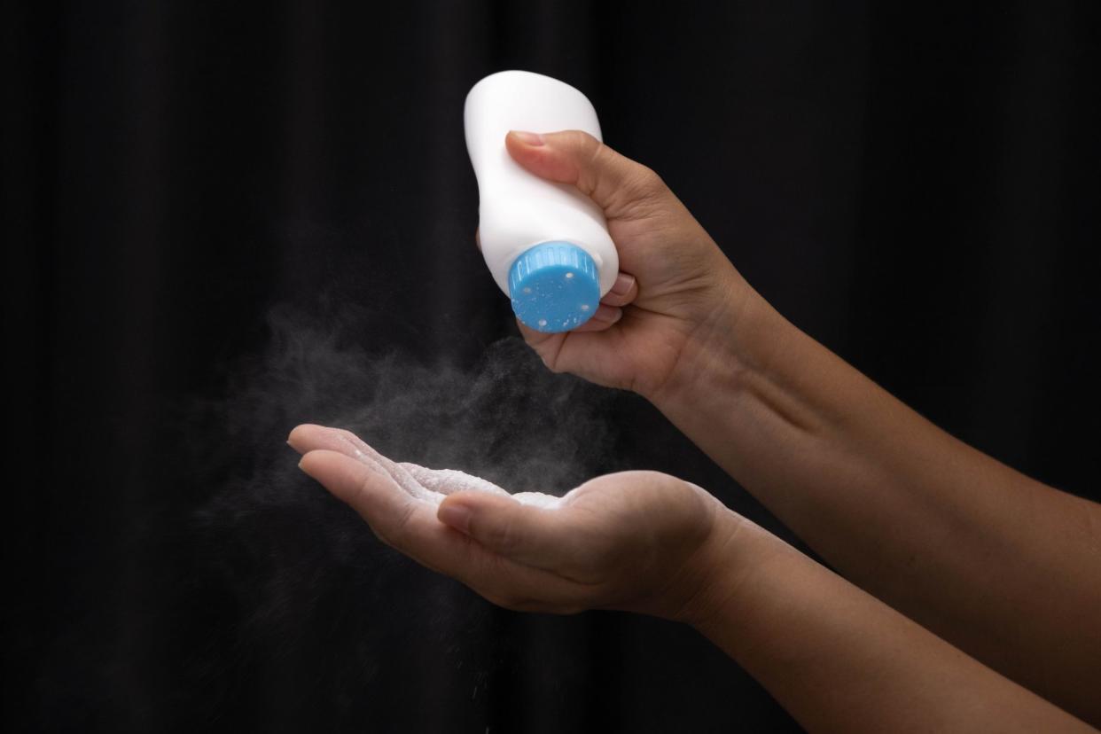 Female hand with talcum powder isolated on black background.