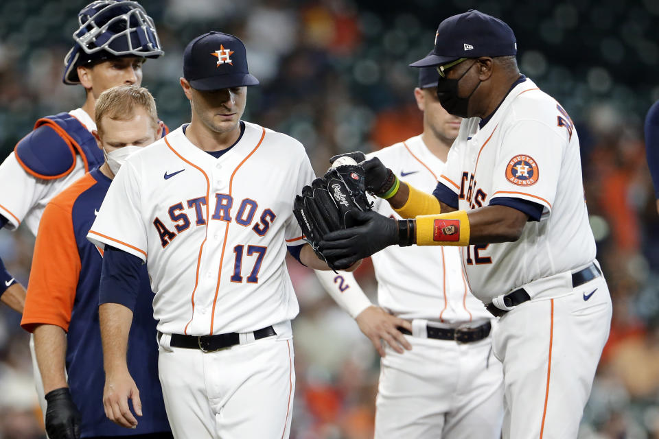 Houston Astros starting pitcher Jake Odorizzi (17) hands the ball off to manager Dusty Baker Jr. (12) as he leaves the mound with an injury on the second batter of the first inning of a baseball game agains the Los Angeles Angels Saturday, April 24, 2021, in Houston. (AP Photo/Michael Wyke)