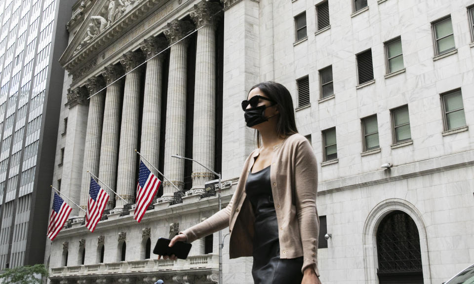 A woman wearing a mask passes the New York Stock Exchange, Tuesday, June 30, 2020, during the coronavirus pandemic. (AP Photo/Mark Lennihan)