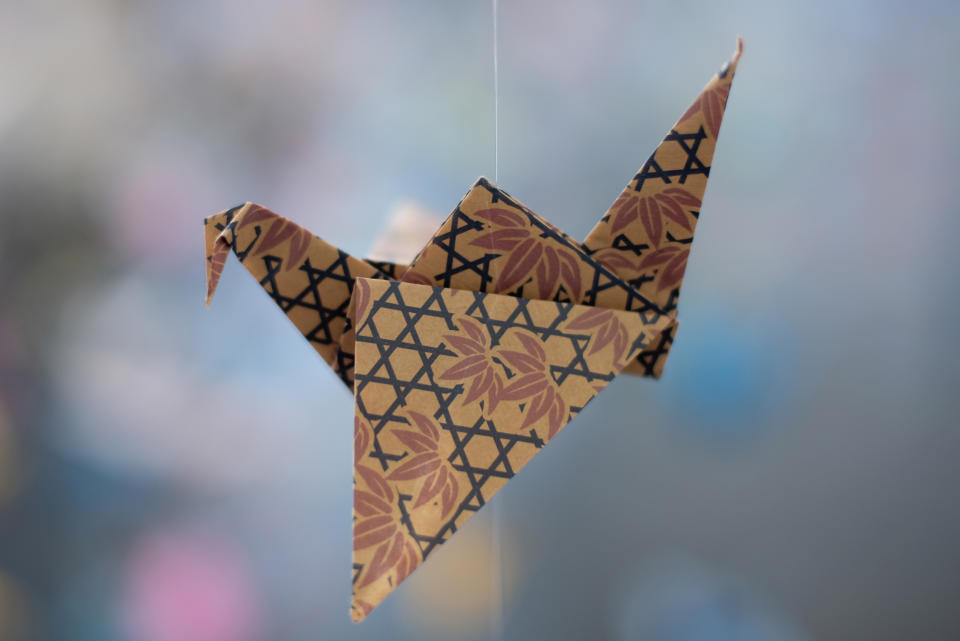 An origami paper crane hangs in the Matter Studio Gallery in Los Angeles, among thousands of others during an exhibit for those who have died in the U.S., of COVID-19, on Tuesday, Aug. 11, 2020. Hundreds of origami now hang from the ceiling of Karla Funderburk’s Matter Studio with others sitting on tables and stacked in boxes waiting to be added to the sad reminder of the virus’ toll. (AP Photo/Richard Vogel)