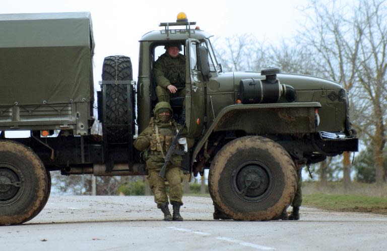 Armed men in military fatigues use a truck to block the road to the Ukrainian military airport of Belbek, near Sevastopol, on March 2, 2014