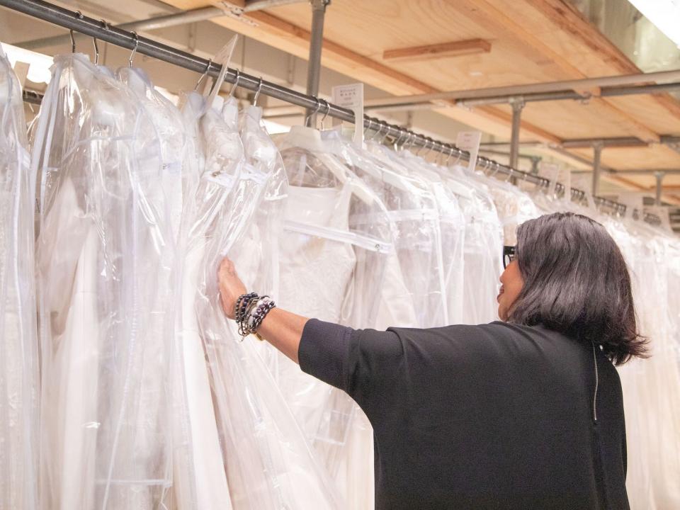 A woman looks at a wedding dress on a rack at Kleinfeld.