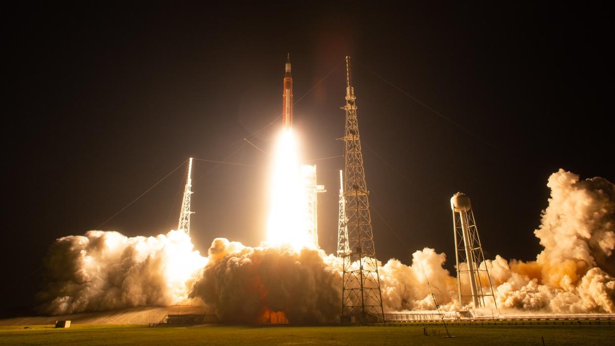  rocket launching into the darkness and spewing smoke below, highlighted in orange 